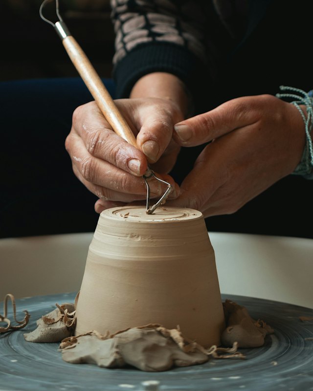 Trimming a pot with a wooden tool