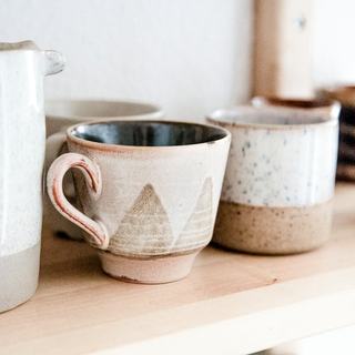 Two cream mugs on a shelf